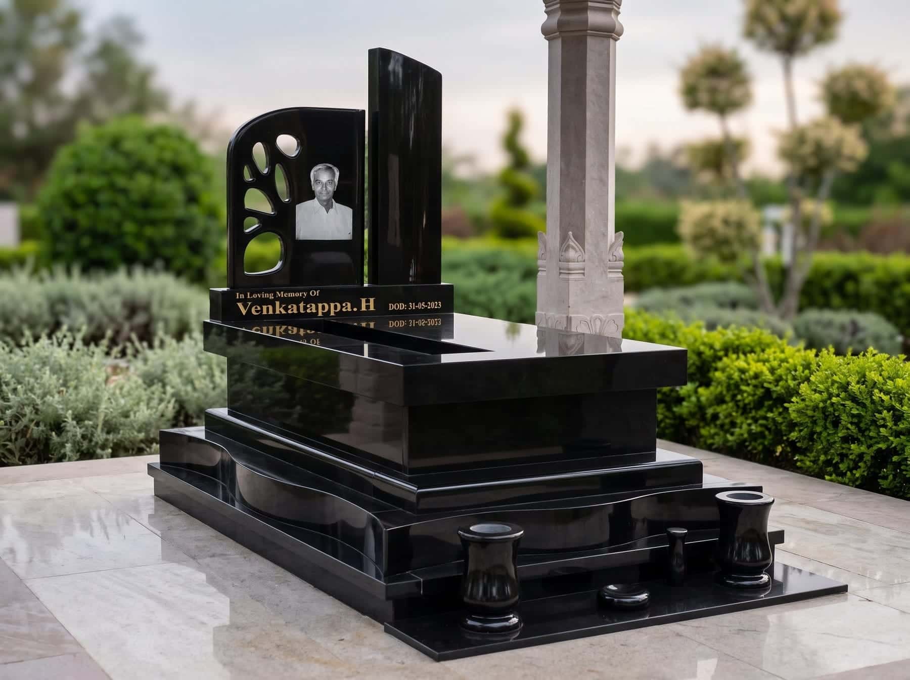 Black granite memorial with an etched portrait, gold lettering and granite urns